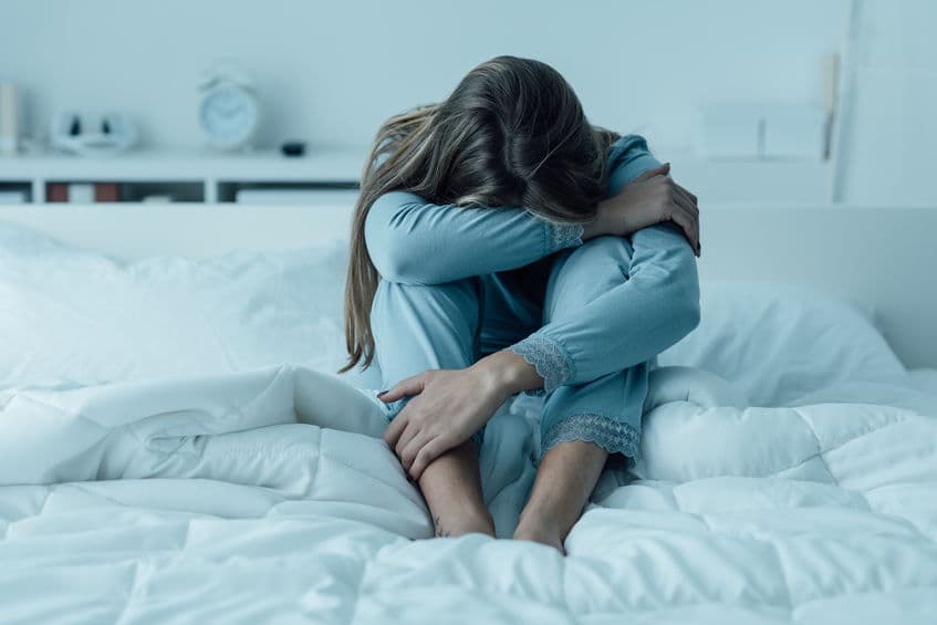 Depressed woman awake in the night, she is exhausted and suffering from IBS